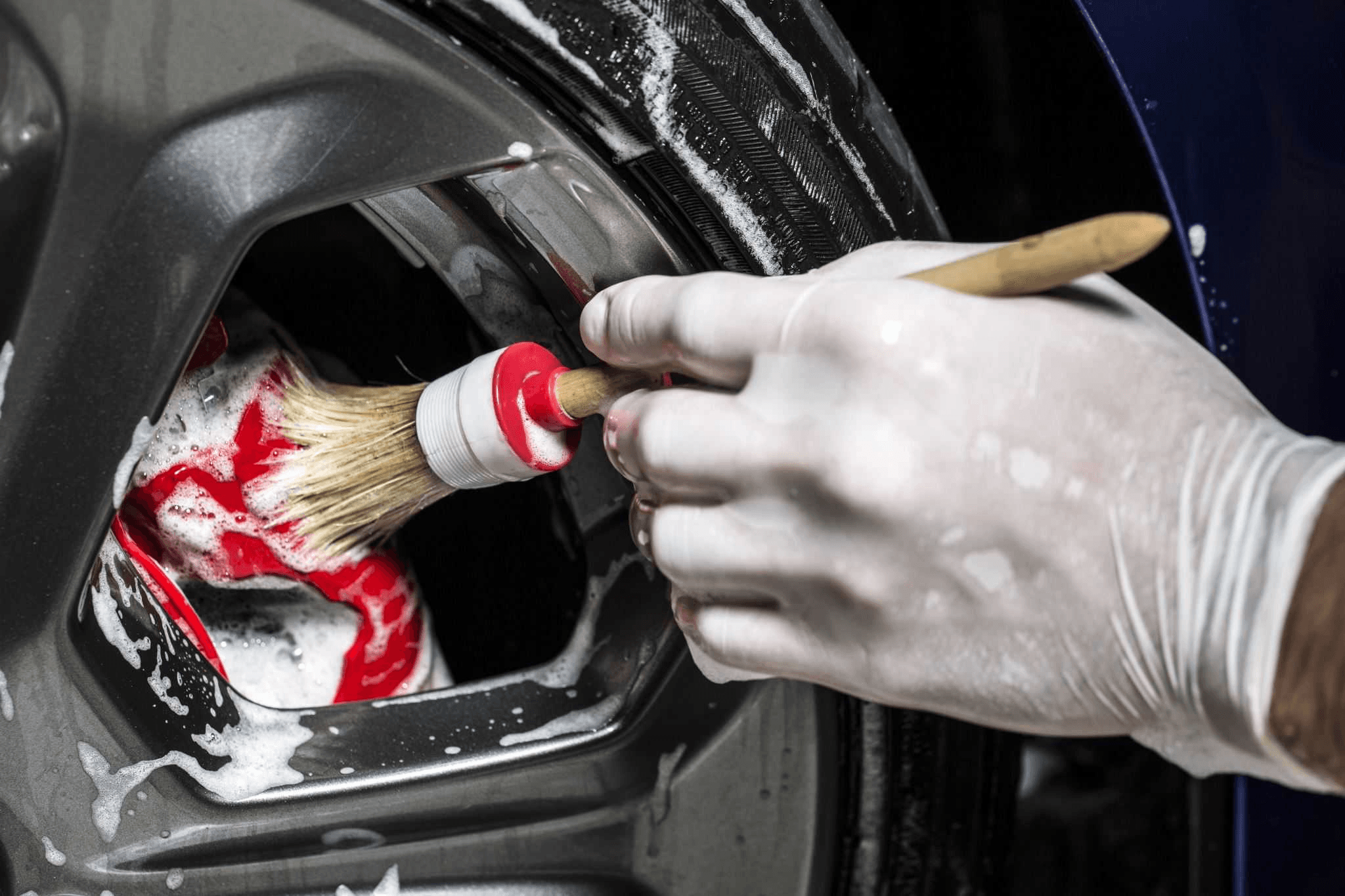 Kolo auta čištěné rukou držící kartáč